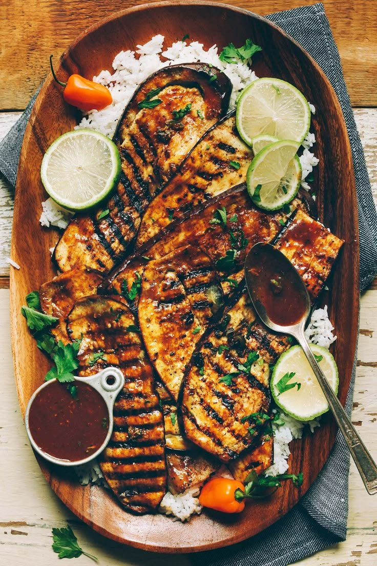 Jamaican jerk grilled eggplant served over rice with whole lemon slices and BBQ sauce on the side